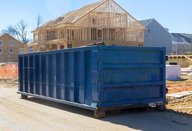 a truck backed up to a line of residential dumpsters, ready for transport